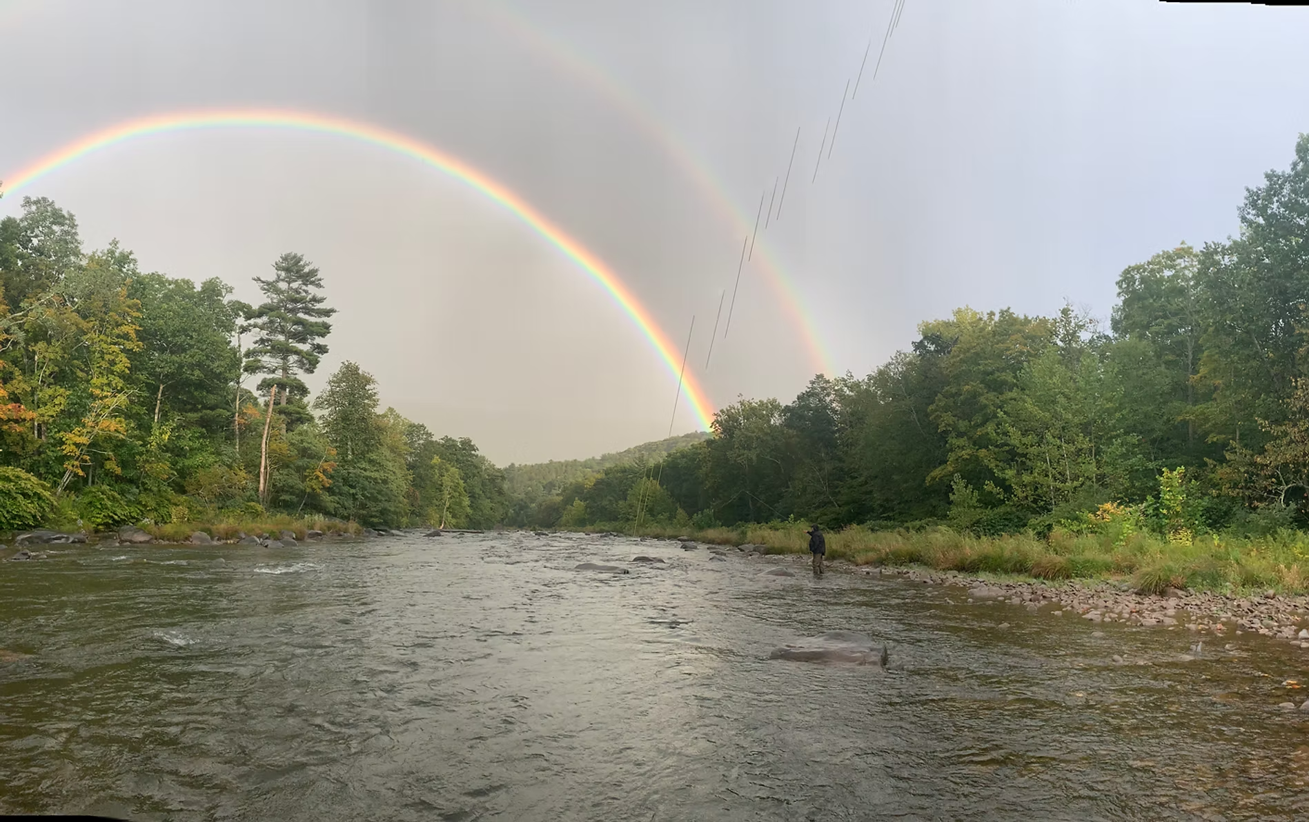 Double rainbow over a Catskill river with an angler fishing